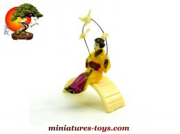 La geisha aux oiseaux assise sur le pont du jardin japonais miniature vintage